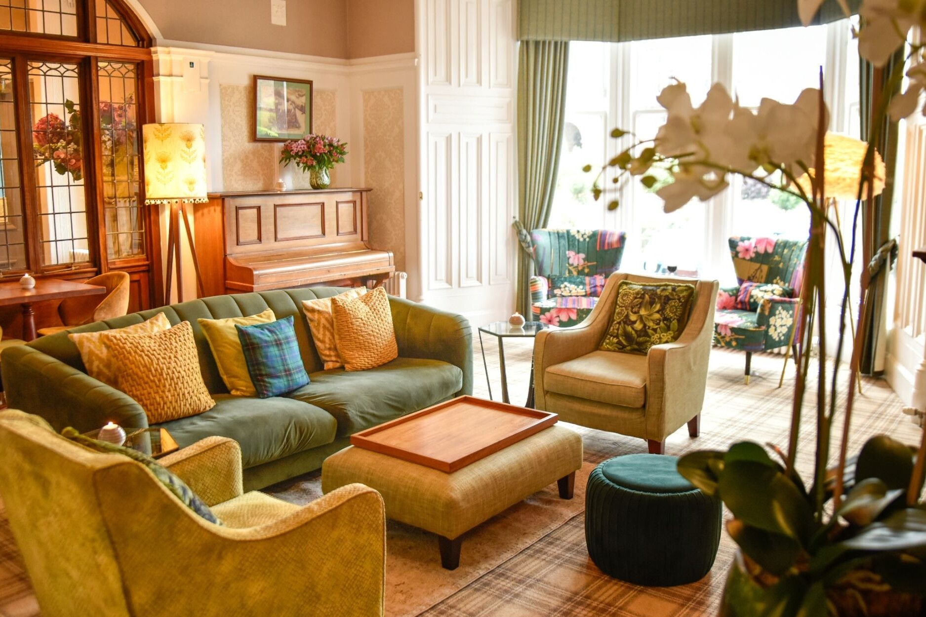 Beautiful velvet sofa with arm chairs and luxury cushions. two armchairs in the bay window. Traditional piano and beautiful floor lamp.